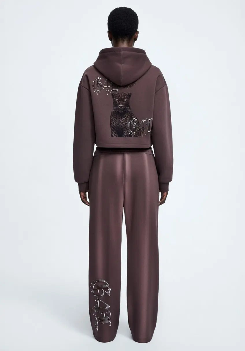 Back view of dark reddish purple cropped zip-up hoodie with graphic design worn with matching pants