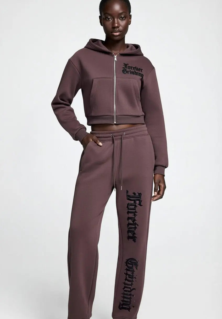 Dark reddish purple cropped zip-up hoodie by ODMPOD worn with matching sweatpants
